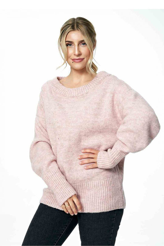 Elegant model showcasing a luxurious loose pink sweater with a boat neckline and ribbed sleeves by Figl, styled with dark jeans.