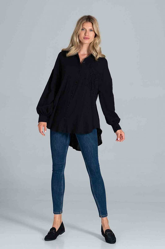 Fashionable model in a black Figl oversized shirt with billowing sleeves and a decorative pocket, elegantly styled with skinny jeans.