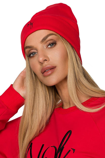 Close-up of a model donning a vibrant red ribbed knit beanie, radiating elegance with delicate embroidered accents, ideal for a trendy seasonal look.