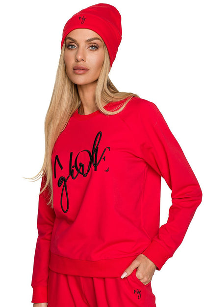 Fashionable woman wearing a red ribbed knit beanie and sweatshirt, exuding luxury, featuring prominent embroidered text for a stylish autumn appearance.