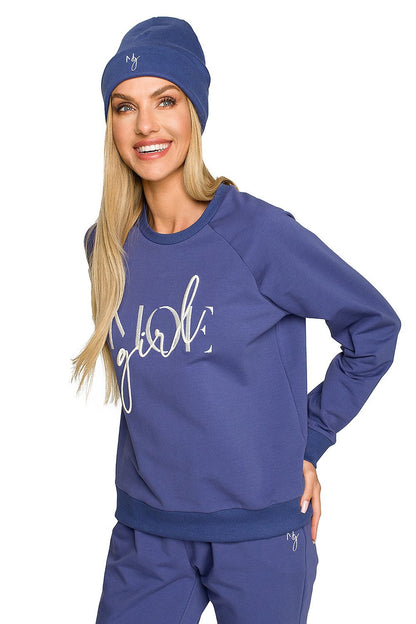 Joyful model in a blue ribbed knit beanie and matching sweatshirt, showcasing exquisite embroidery and a relaxed yet elegant vibe for autumn wear.