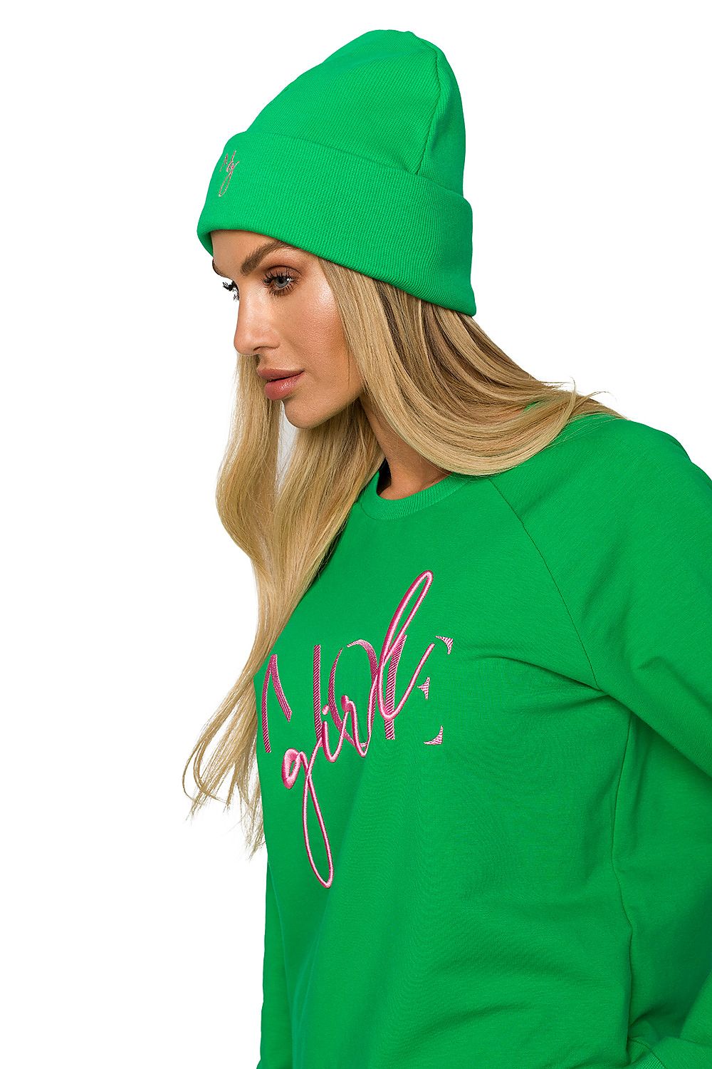 Profile view of a fashionable woman wearing a green ribbed knit cap adorned with delicate embroidery, paired with a stylish green sweatshirt, highlighting her trendy ensemble.