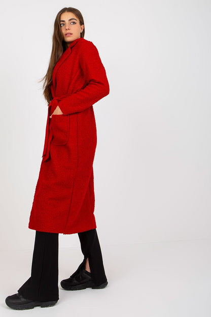Side view of a luxurious red coat by Och Bella, designed with a tie belt and patch pockets, modeled by a chic woman exuding effortless style.