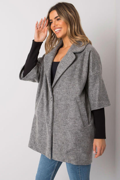 Chic grey coat in a loose fit by Rue Paris, featuring a single button and pockets, elegantly styled on a female model with warm lighting.