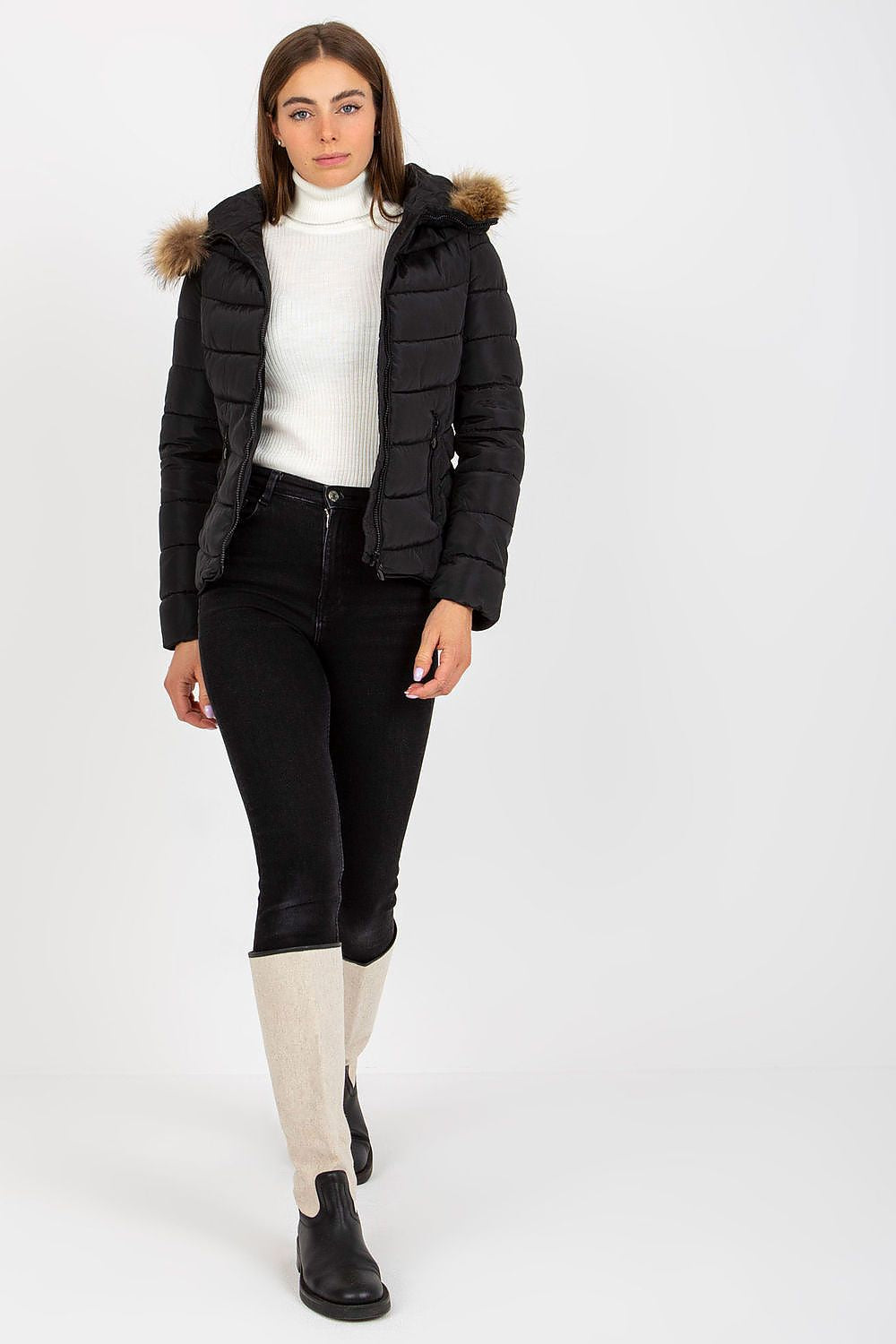 Chic winter look featuring a black puffer jacket with a fur-trimmed hood, model wearing stylish black jeans and a white turtleneck.