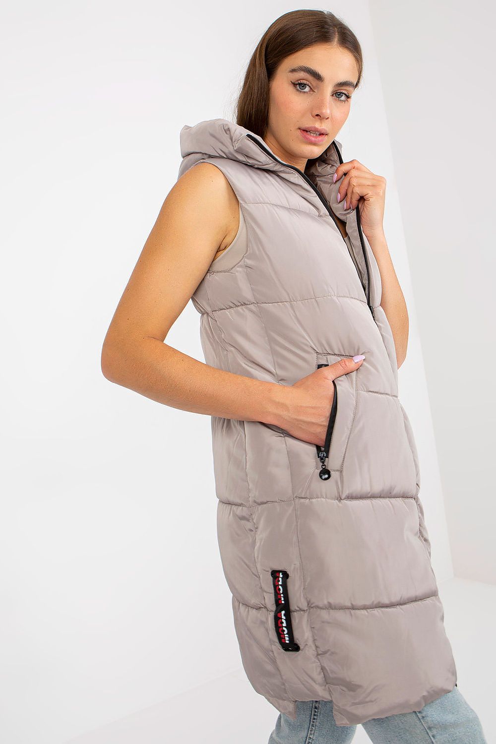 Side view of the Elegant NM Gilet in light grey, highlighting its sleek design with practical pockets and stylish hood, perfectly paired with denim for an effortless luxury vibe.