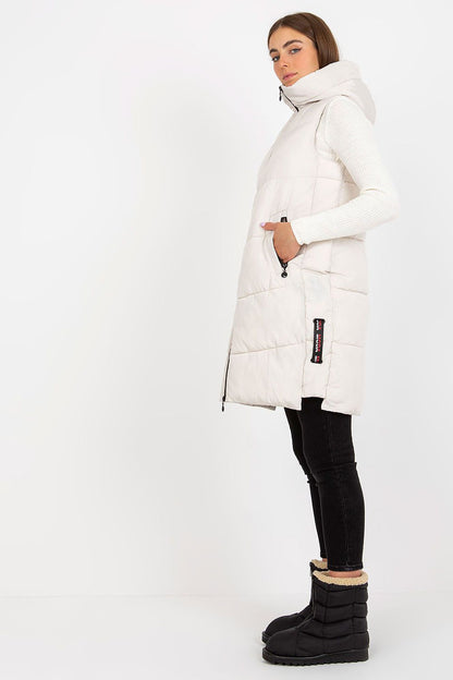 Model wearing the Elegant NM Gilet in a pristine white, beautifully complemented by black skinny jeans, exuding refinement and modern elegance with its puffy silhouette and trendy hood.