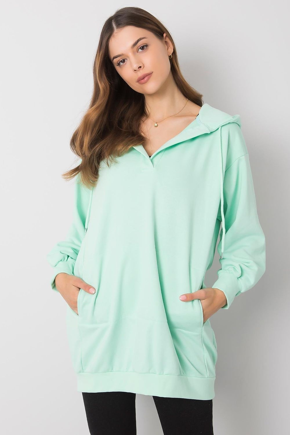 Elegant women's hooded sweatshirt in mint green, featuring a kangaroo pocket and extended cut, ideal for casual wear and stylish comfort.