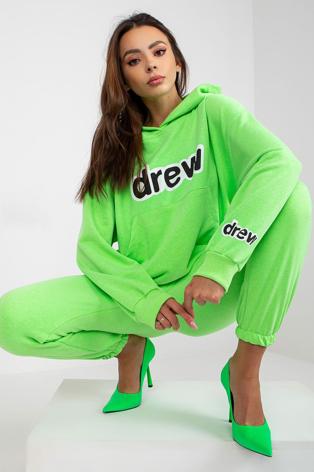 Chic neon green hoodie and jogger pants ensemble, showcasing a modern oversized fit and stylish detailing, paired with striking green high heels for a sophisticated athleisure style.