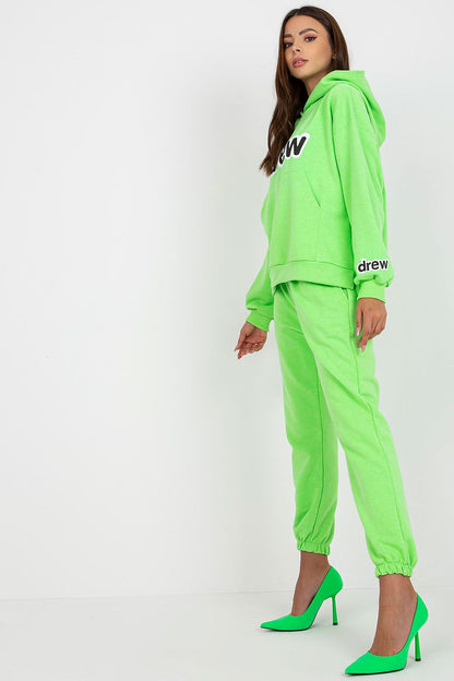 Stylish women’s luxe cotton-blend sweatshirt and pants set in vibrant green, featuring a hood and kangaroo pocket, complemented by chic green heels.
