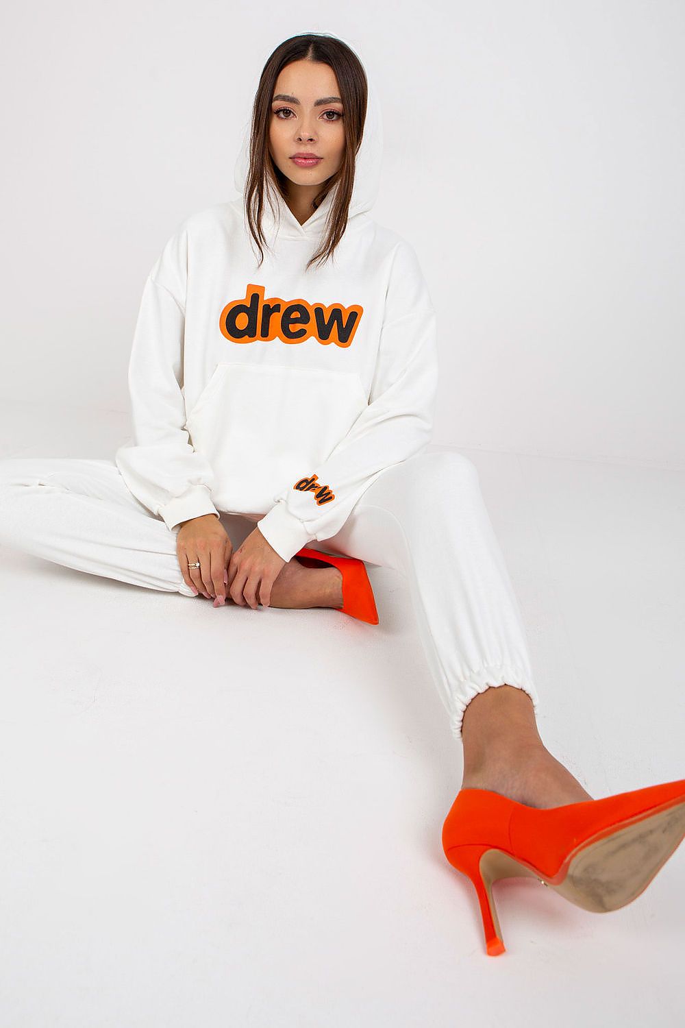 Sophisticated display of a white luxe cotton-blend sweatshirt set, featuring an oversized fit, paired with orange stilletos for a touch of glamour.