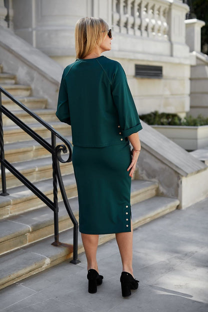 Back view of a woman in a luxurious Morgan knit two-piece set with stylish metallic press studs, exuding elegance as she stands on a staircase, highlighting the chic silhouette of the outfit.