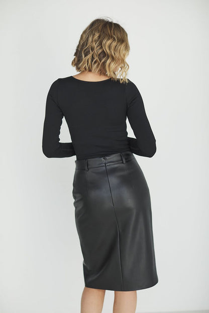 Back view of a sophisticated model in a sleek black eco leather skirt, highlighting the structured design and exquisite chain detail, paired with a classic black long-sleeve top.