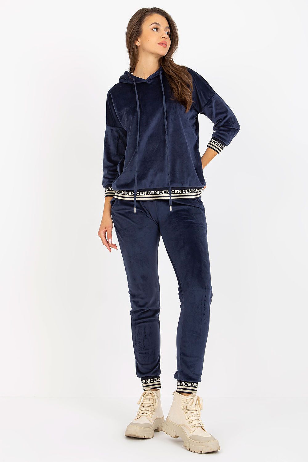 Chic women's velour set in navy featuring a stylish hooded sweatshirt and slim-fit pants, paired with trendy footwear for a fashionable look.