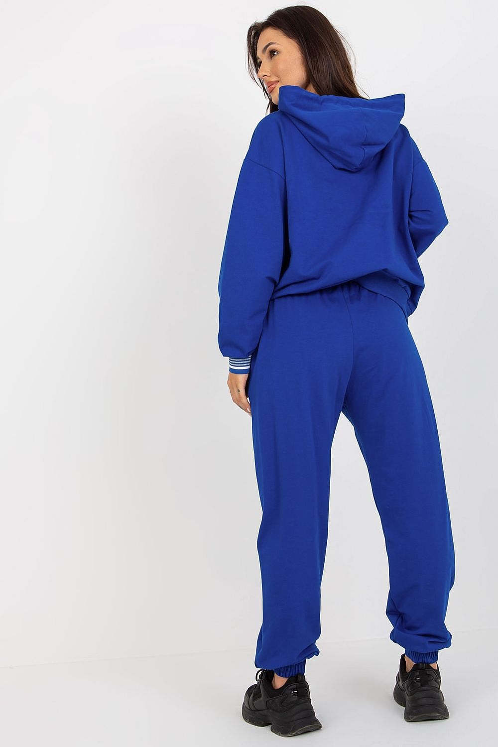 Elegant back view of a woman in a striking blue cotton blend sweatshirt and trousers set, highlighting the fashionable hood and relaxed fit, ideal for luxury loungewear.