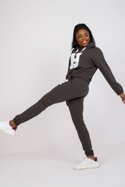 Chic model elegantly posing in dark grey luxury hoodie and pants set, highlighting comfort and fashion with stylish sneakers.