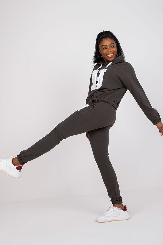 Chic model elegantly posing in dark grey luxury hoodie and pants set, highlighting comfort and fashion with stylish sneakers.
