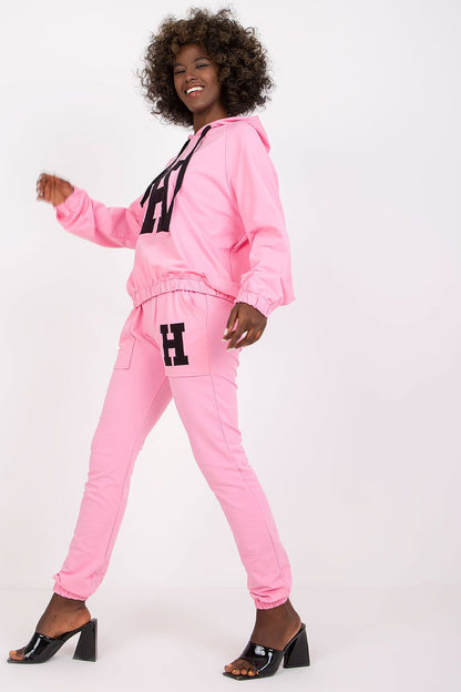 Elegant woman in a luxurious pink sports outfit, playfully walking, showcasing the blend of comfort, style, and contemporary design.