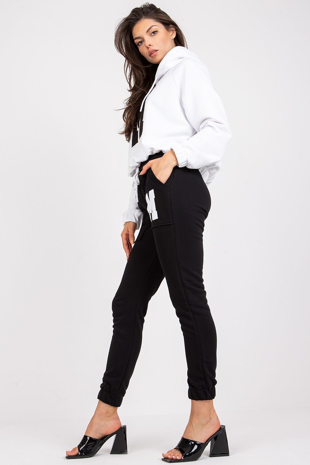 Chic side profile of a model wearing a premium cotton and spandex tracksuit, combining comfort and style with a hooded top and elasticated pants.