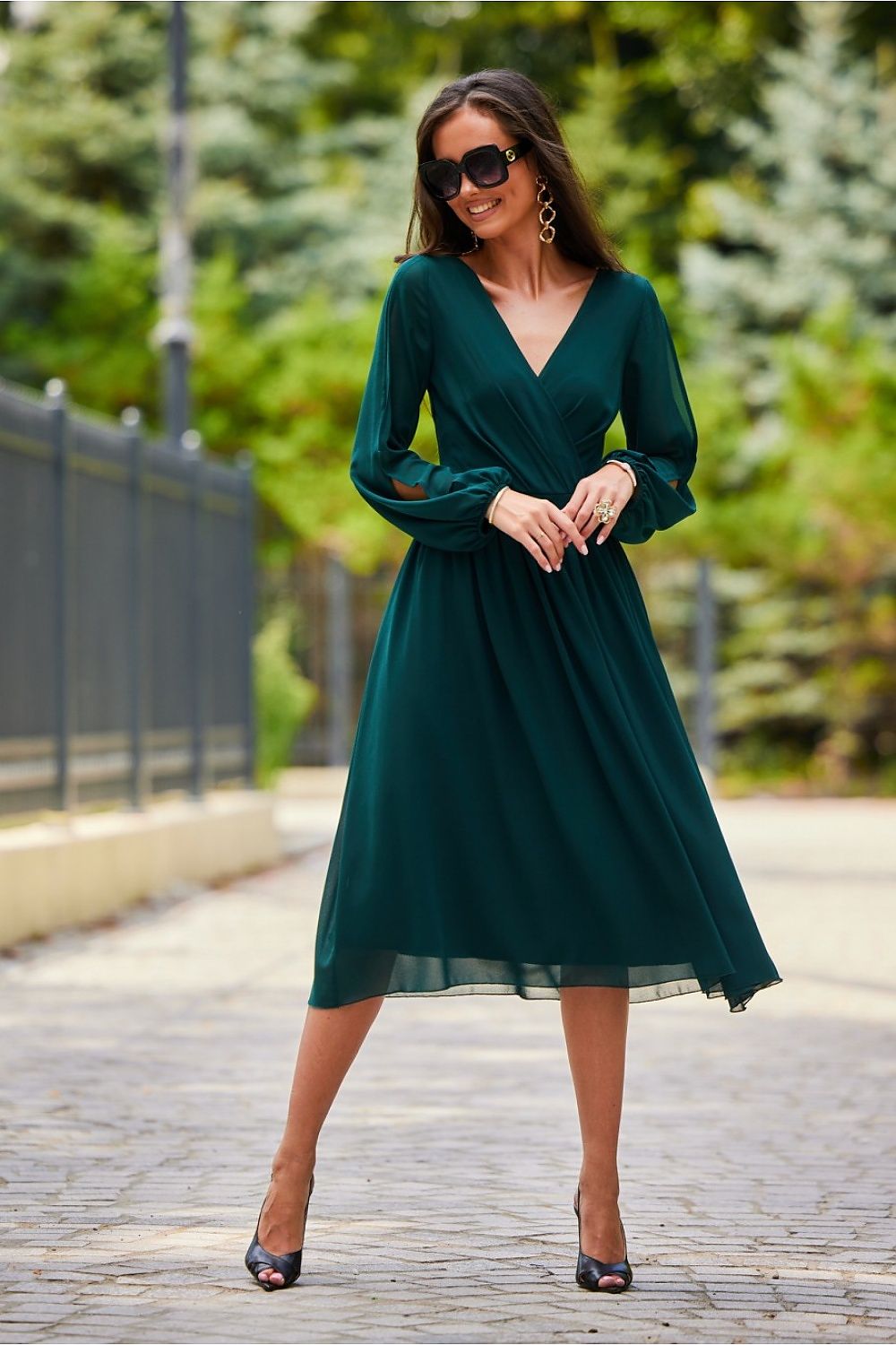 Stunning photograph of a model in a green midi cocktail dress with long buff sleeves and a sculpted back, ideal for upscale occasions.