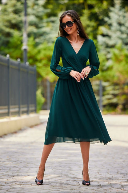 Stunning photograph of a model in a green midi cocktail dress with long buff sleeves and a sculpted back, ideal for upscale occasions.