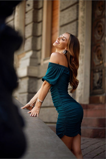 A fashionable woman wearing a fitted crinkle brocade mini dress with a Spanish neckline and ruched detailing, posing gracefully while radiating confidence and elegance.