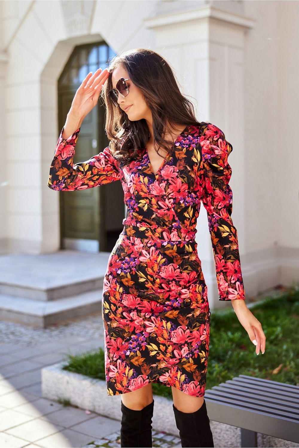 Sophisticated model in a floral patterned mini dress with puff sleeves, enjoying the outdoor sunshine and expressing elegance.