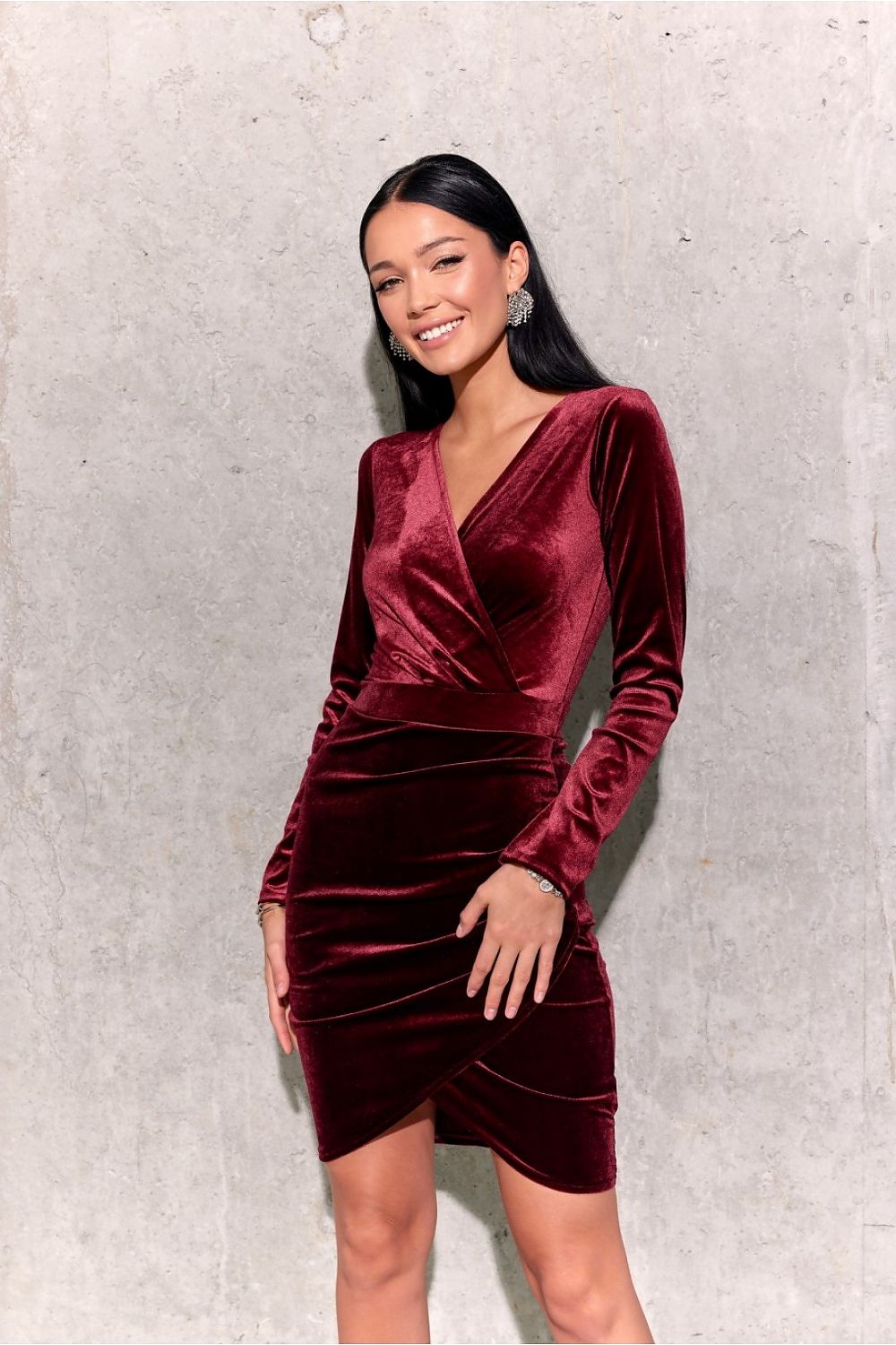 Radiant woman wearing a burgundy velvet evening dress, elegantly styled for a glamorous night out, radiating confidence and sophistication.