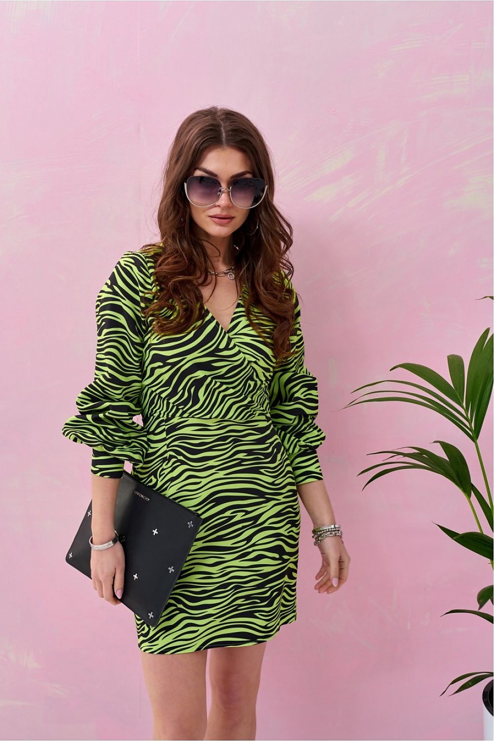 Elegant mini dress in vibrant zebra pattern with a deep neckline and puffed sleeves, styled with oversized sunglasses against a pastel pink background, perfect for chic celebrations.