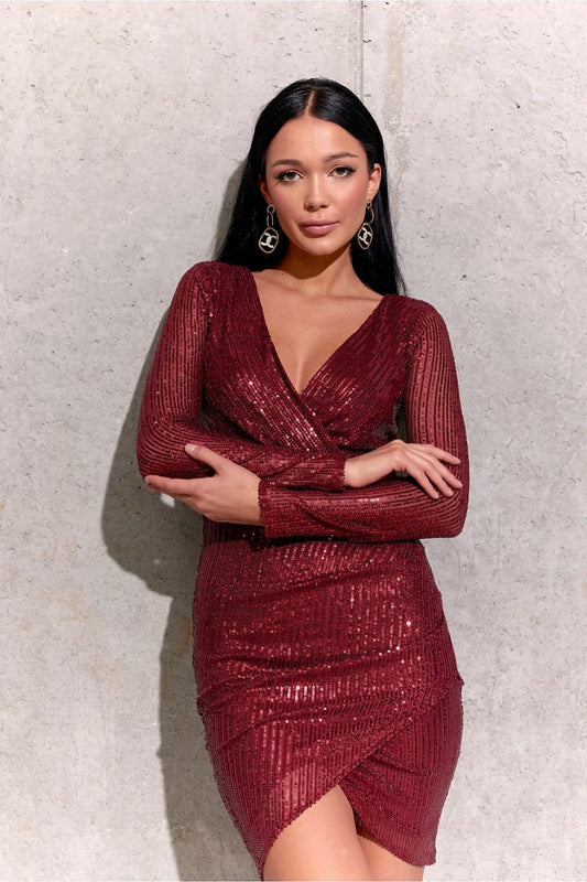 Elegant model posing in a stunning red sequin mini dress featuring a V-neckline and overlapping hem, ideal for sophisticated evening occasions, set against a sleek concrete backdrop.