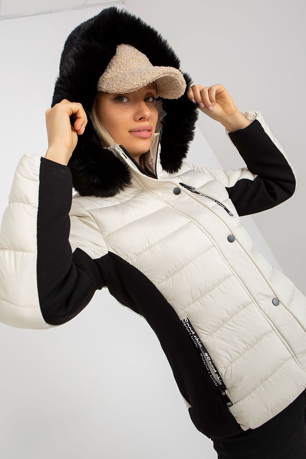Elegant woman showcasing a luxury quilted down jacket with a detachable hood and faux fur trim, exuding style and warmth. The jacket features a contemporary design with zippered pockets, accentuating a chic winter look.
