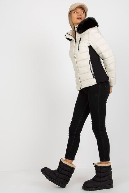 Fashion model showcasing a luxury quilted down jacket with detachable hood and faux fur, paired with stylish black jeans and boots, creating an elegant winter look.