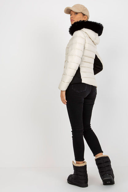Back view of a fashion model in a luxury quilted down jacket with faux fur hood, embodying modern winter elegance while wearing black jeans and trendy winter boots.