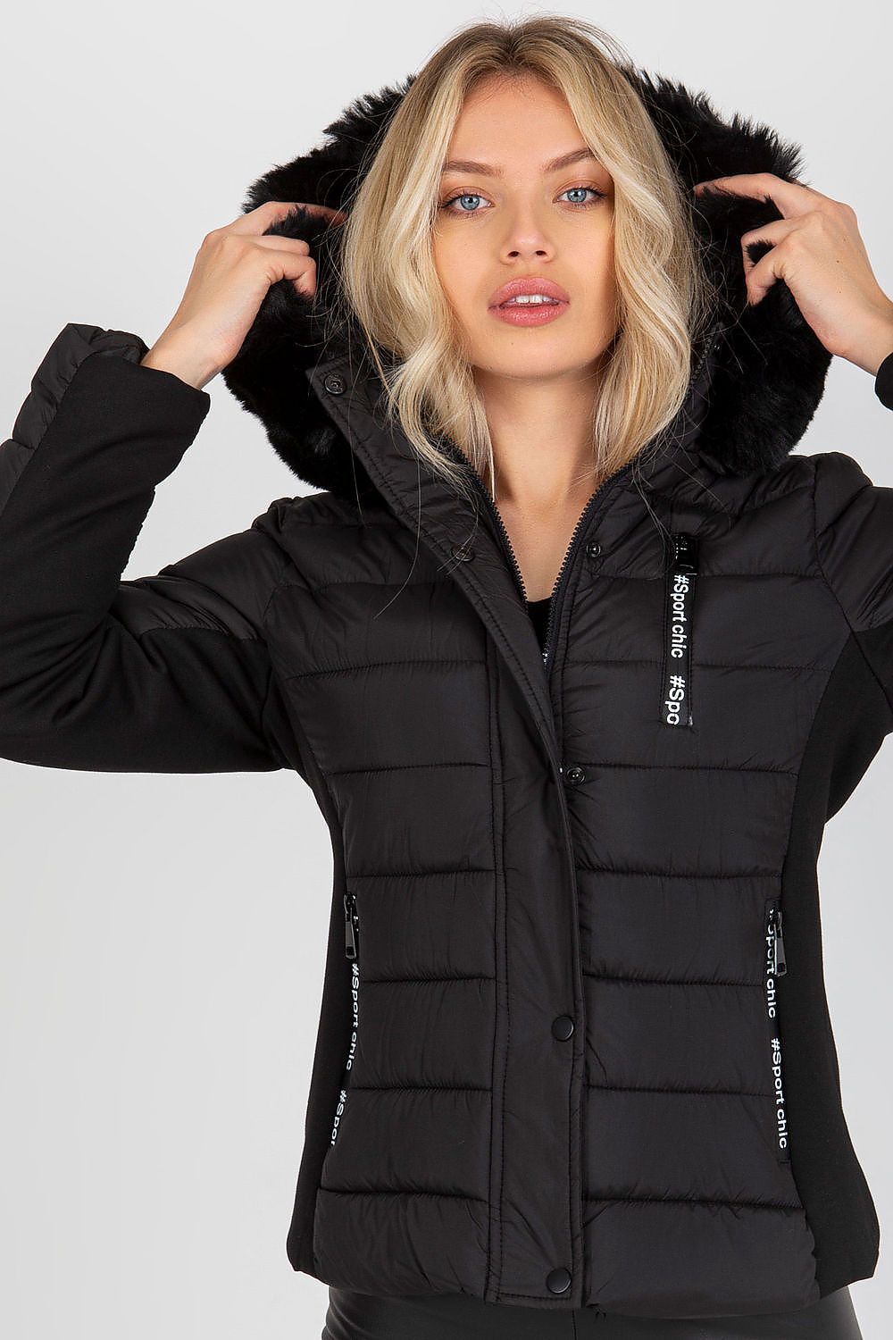 Close-up of a fashion model presenting a luxury black quilted down jacket with a faux fur hood, exuding sophistication and style.