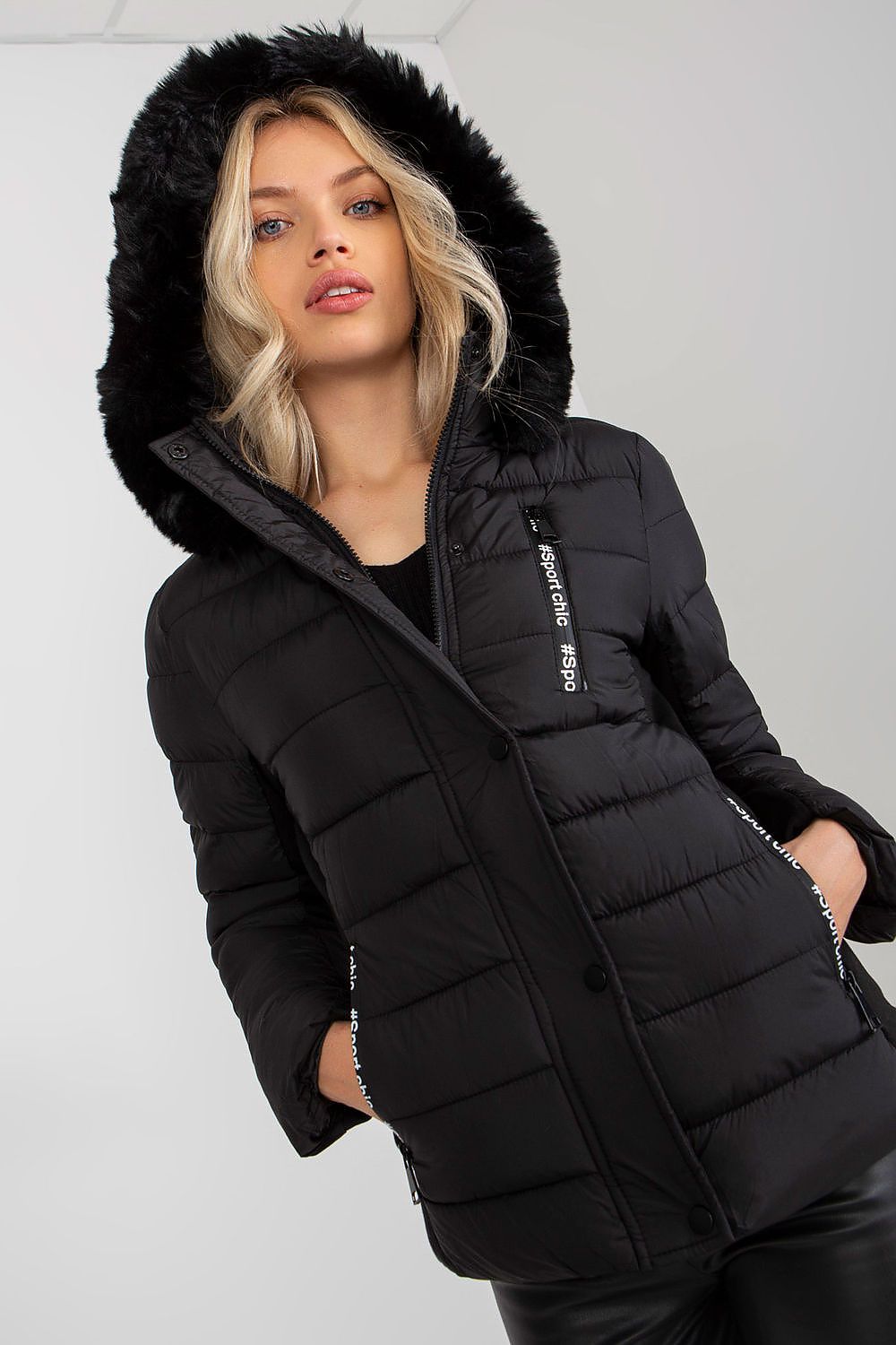 Front view of a fashion model wearing a luxury black down jacket with a detachable faux fur hood, accentuating a fashionable winter ensemble.