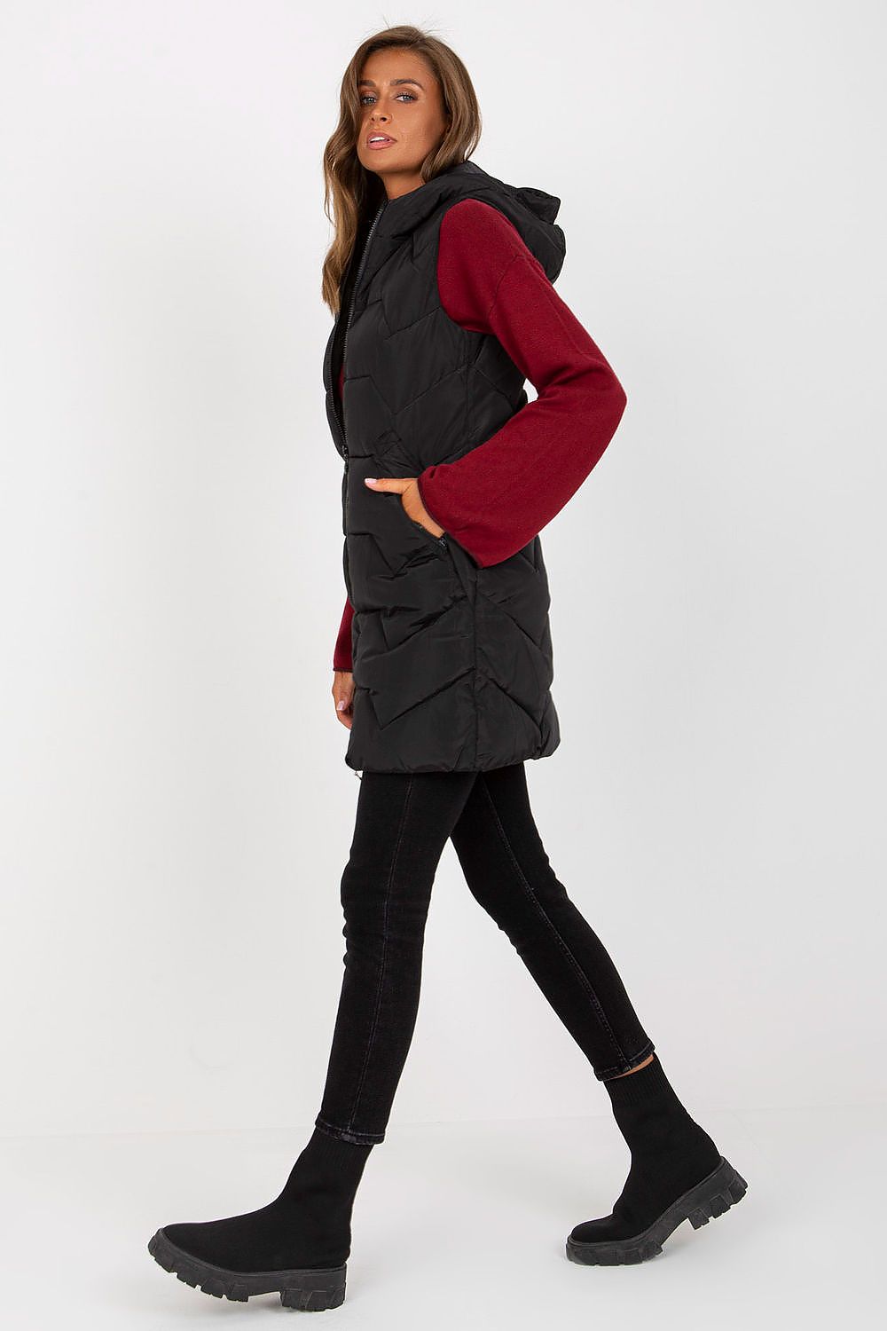 Side view of a woman in a black NM gilet, accentuating the vest’s stylish cut and practicality. The luxury vest is ideal for any modern outfit.