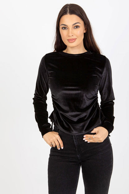 Elegant black velour blouse with long sleeves, featuring adjustable side ties, modelled by a woman with a natural look. Perfect for a luxurious outfit.