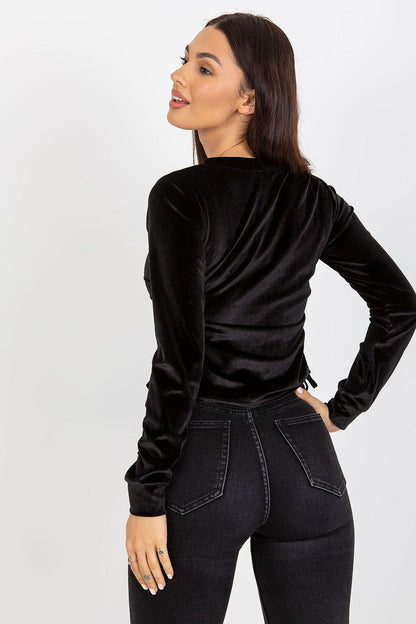 Stylish back view of a black velour long-sleeve blouse, emphasising its luxurious fabric and adjustable features on a model.