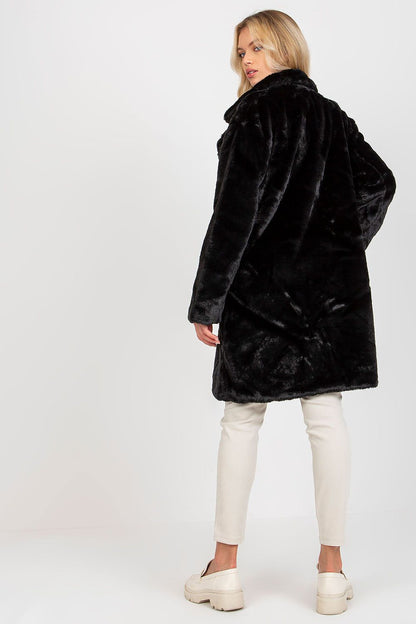 Elegant black fur coat by Och Bella showcased from the back, highlighting its luxurious texture and sophisticated design, paired with chic white trousers.