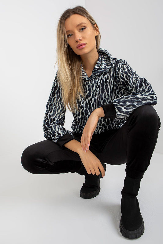 Sophisticated view of a model in the Luxurious Rue Paris Velour Set, featuring an animal print sweatshirt and fitted black velour pants, emphasizing comfort and style.