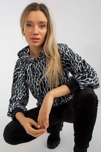Stylish close-up of a model in the animal print velour sweatshirt from Rue Paris, looking fashionable and relaxed while wearing sleek black trousers.