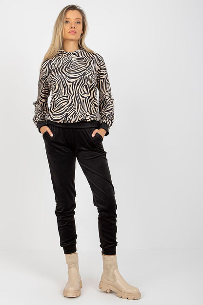Elegant model wearing the Luxurious Rue Paris Velour Set, featuring a striking zebra print sweatshirt with a kangaroo pocket, paired with black velour pants, perfect for chic casual wear.