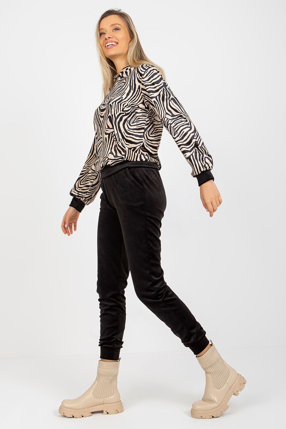 Luxurious Rue Paris velour set featuring a stylish animal print sweatshirt and comfortable long pants; model showcasing the elegant outfit with a joyful pose.