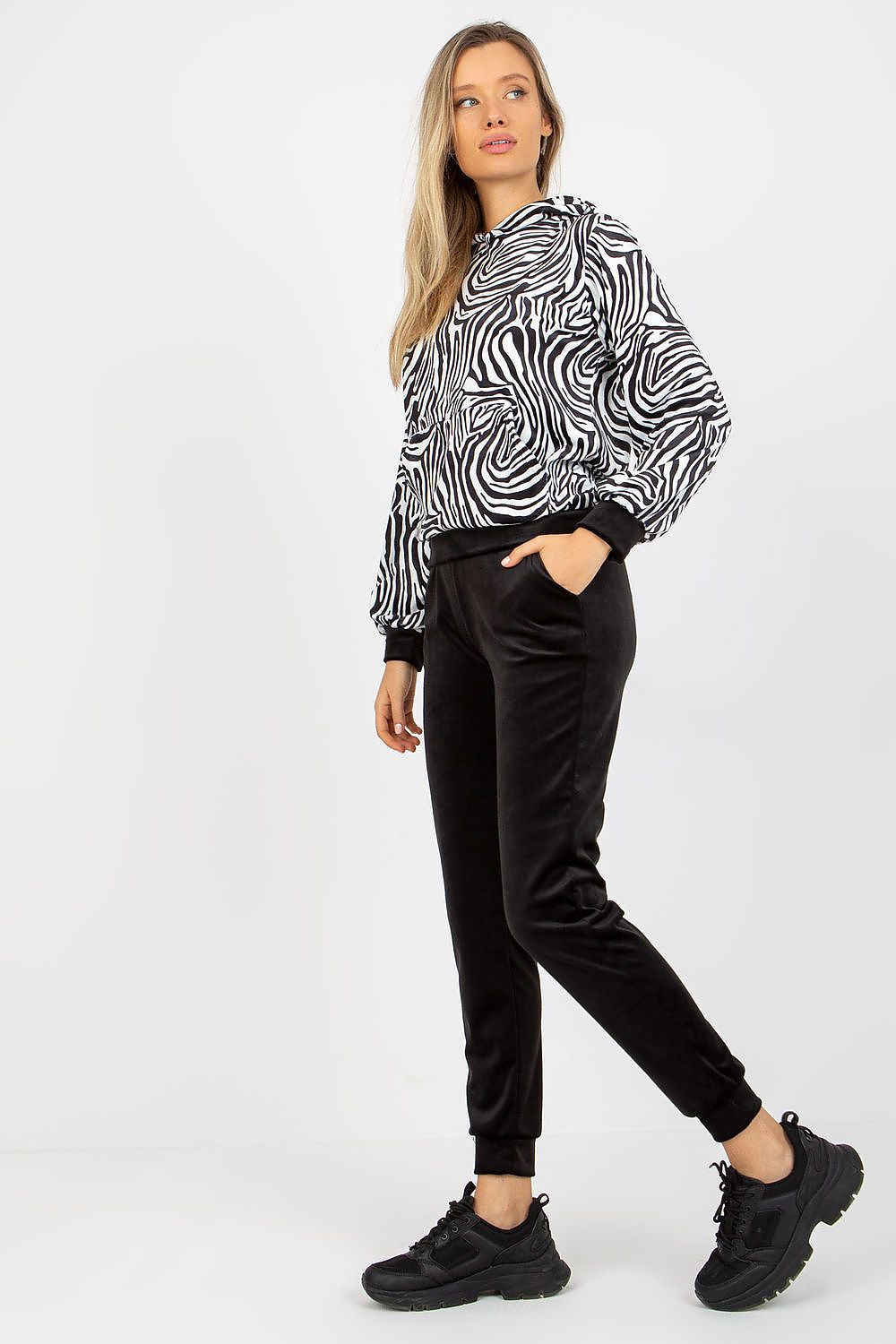 Fashion-forward model in the Rue Paris animal print velour set, pairing the outfit with sporty black shoes, embodying an effortless blend of luxury and casual wear.