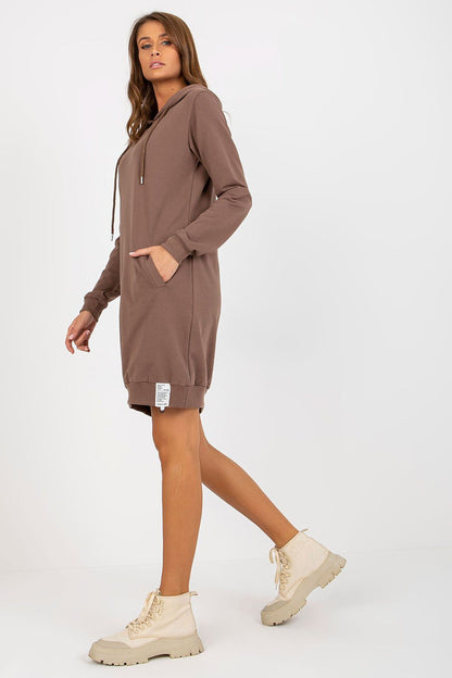 Elegant woman showcasing a brown hooded sweat dress with long sleeves and pockets, styled with chic beige ankle boots.