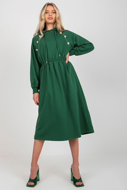 Elegant woman showcasing a casual cotton hoodie dress in rich green shade, featuring long sleeves, a drawstring hood, and decorative buttons, perfect for a contemporary everyday look.