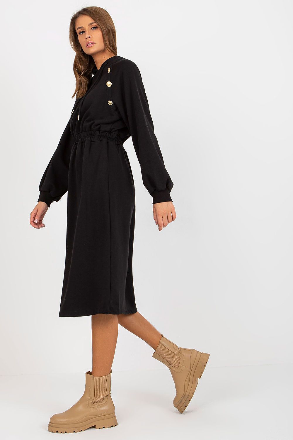 Chic black hoodie dress showcased on a model, featuring a cinched waist and decorative buttons, paired with trendy ankle boots.
