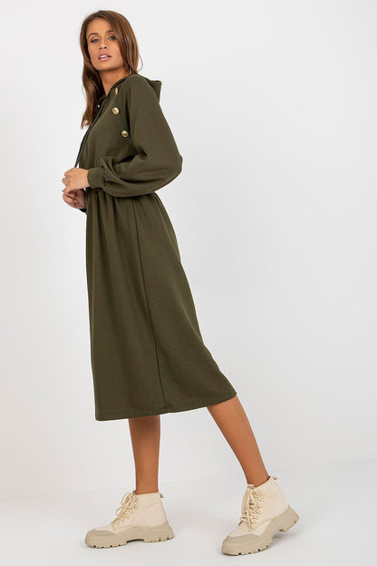 Trendy olive green hoodie dress modelled elegantly, featuring button details and a fitted waist, styled with chic footwear.