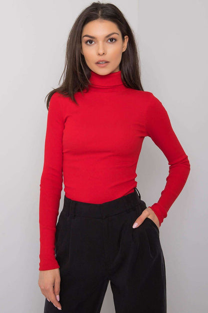 Elegant model wearing a fitted red cotton turtleneck, exuding sophistication with long sleeves, paired with stylish black trousers for a chic look.