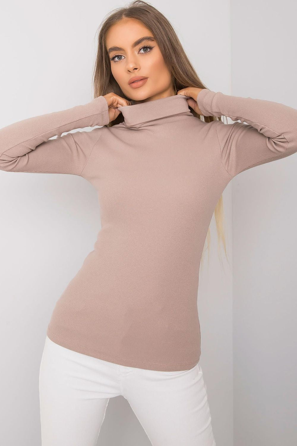 Luxurious fitted beige cotton turtleneck, model posing with a fashionable look, showcasing long sleeves and a sophisticated silhouette.